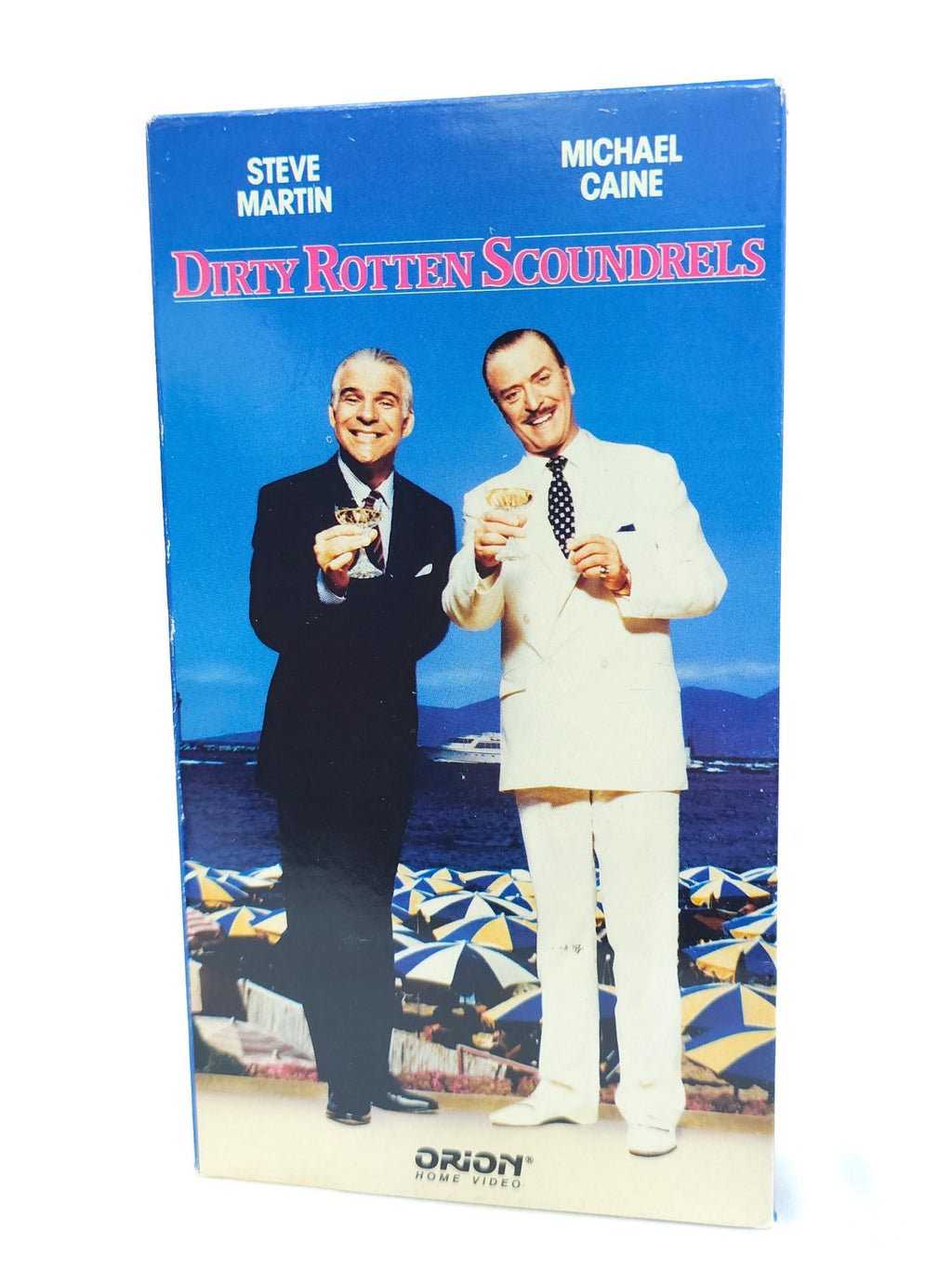 VHS cover of 'Dirty Rotten Scoundrels' with two men on a boat, featuring Steve Martin and Michael Caine.